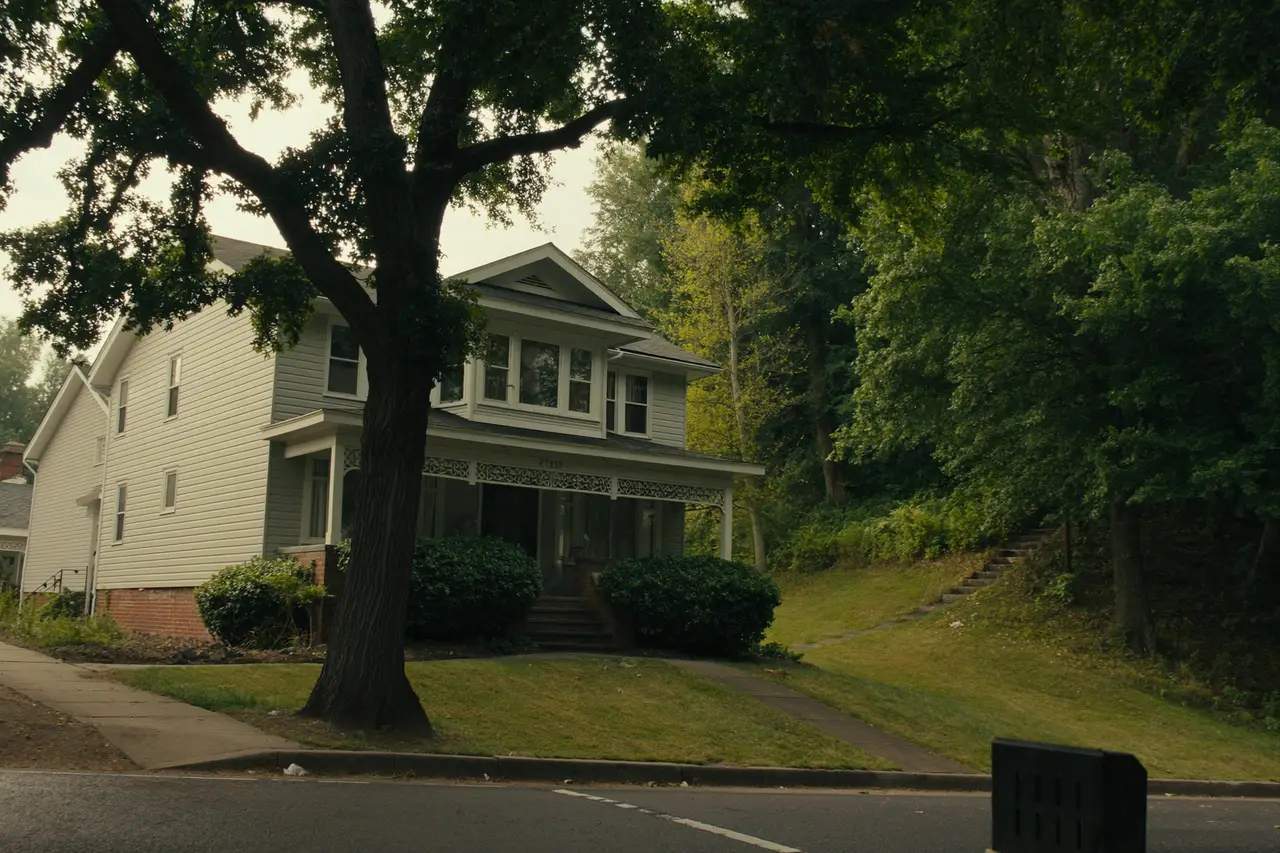 Rendered image of a two-story house with a porch among tall trees