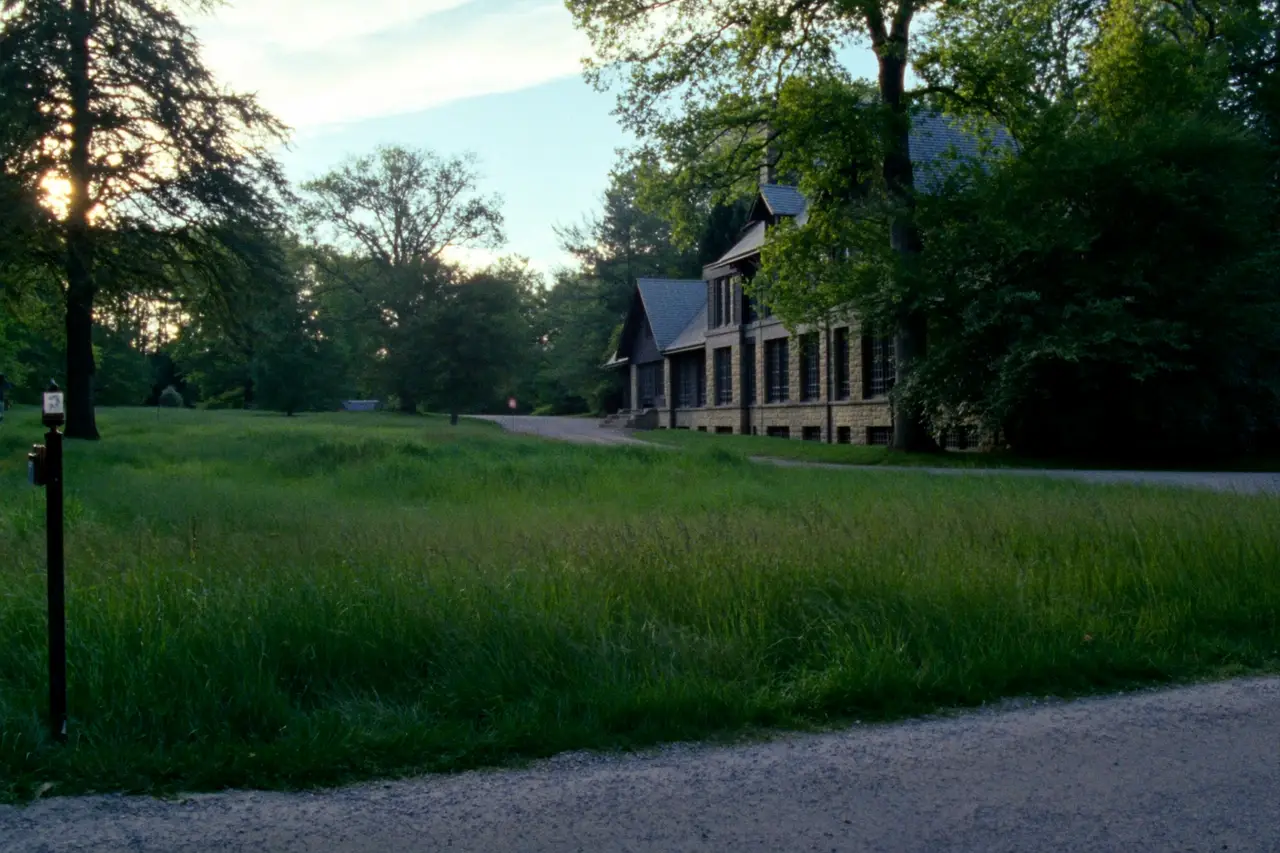 Rendered image of a large house set back on an estate lot with meadow and trees
