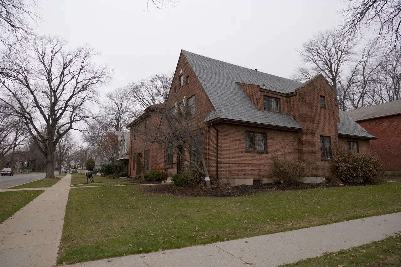 Rendered image of a 1920s brick Tudor house with a slate roof on a tree-lined street