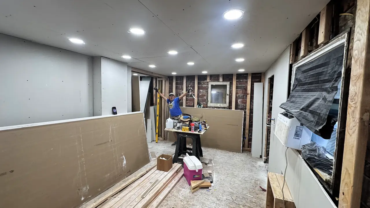 Basement with new drywall hung and recessed ceiling lights on, before paint.