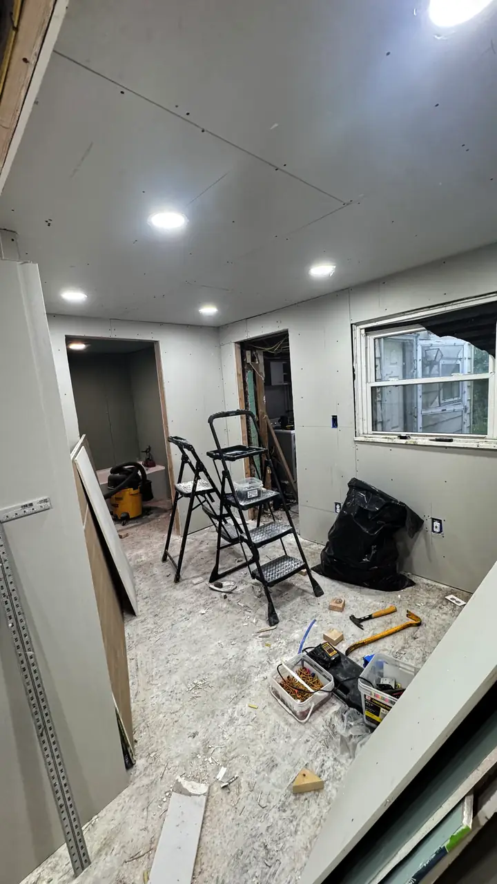 Basement drywall and recessed ceiling lights, ladder in the corner.