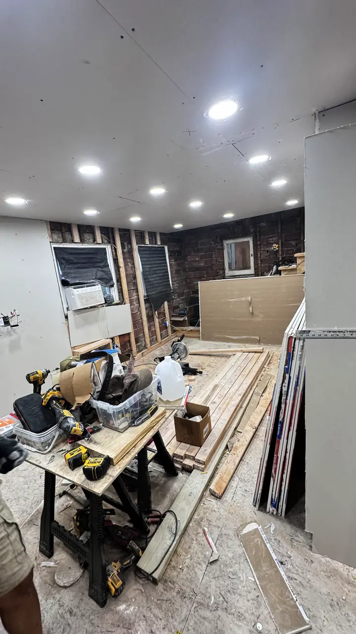 Basement wall board hung, tools and a saw on the floor.
