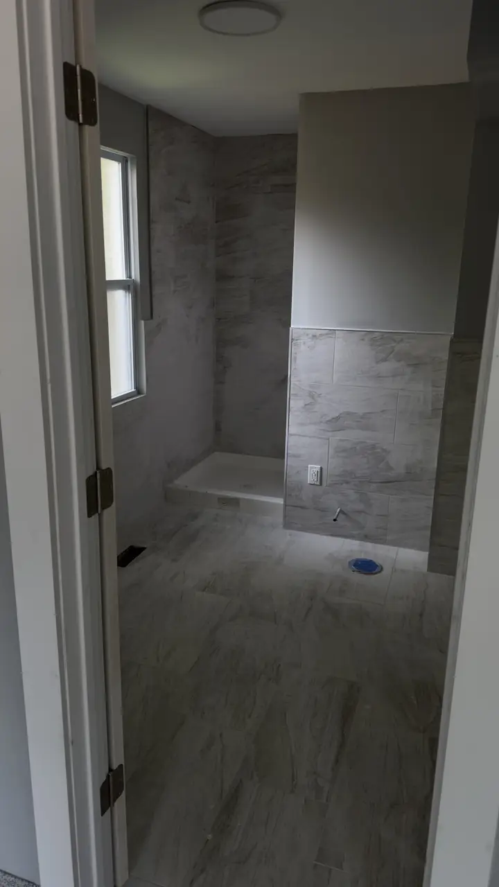 Finished bathroom with large-format wall tile to the ceiling and a tiled floor.