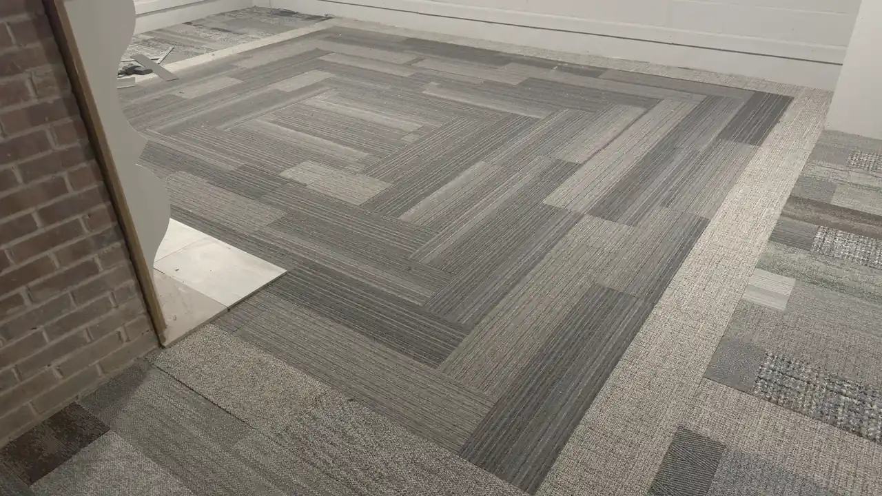 Carpet tile laid in a quarter-turn pattern against a brick wall.