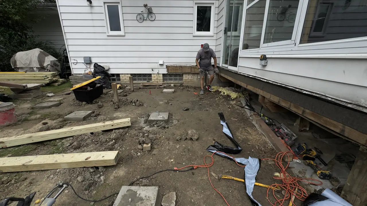 Ledger and joists for a new deck against a white clapboard house.