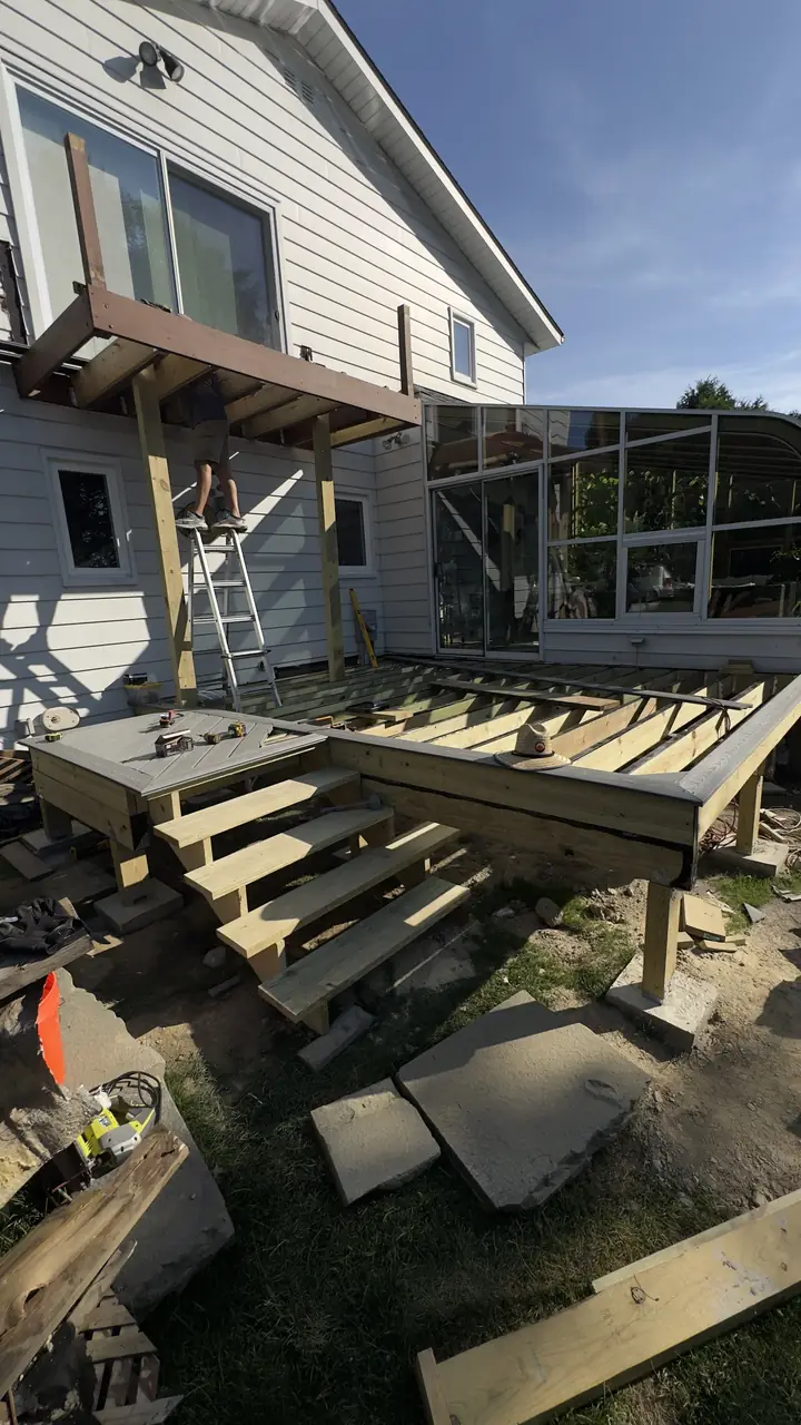 Deck stair stringers and landing framed against a white house.