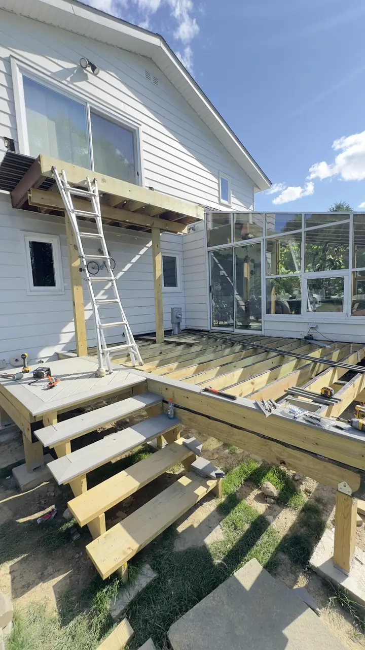 Deck frame with stairs framed, before decking boards, under a clear sky.