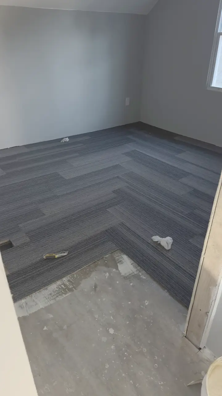 Dark luxury vinyl plank floor installed in an empty room, trim not yet on.