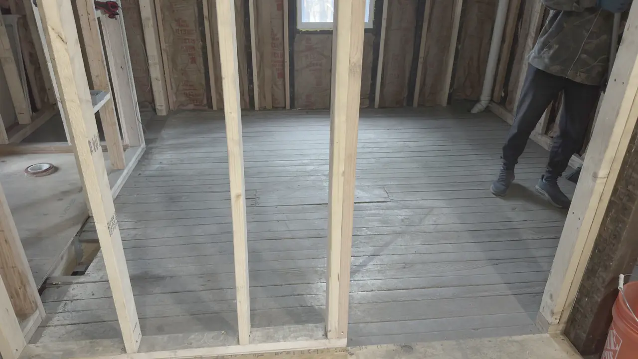 New stud wall framed in a basement, subfloor swept.