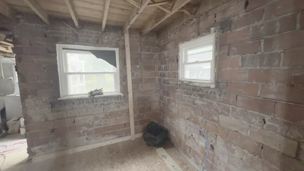 Brick basement walls with new framing and two windows.