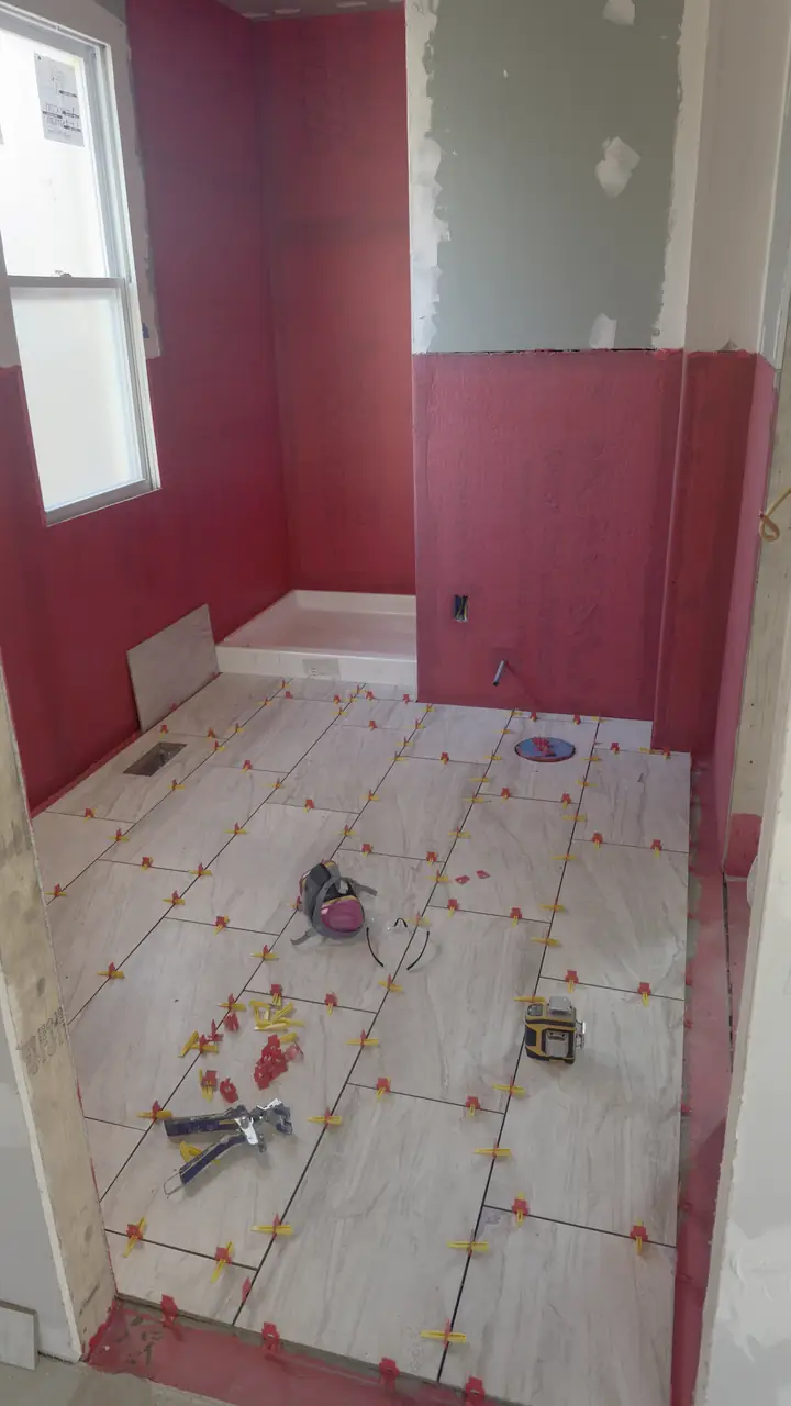 Bathroom floor tile set and walls waiting for tile, window above the tub.