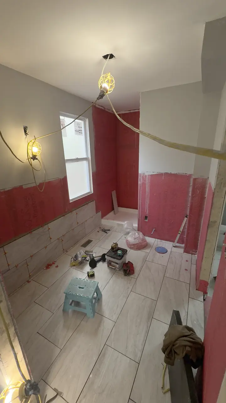 Bathroom floor tile grouted, wall tile partly set around the tub.